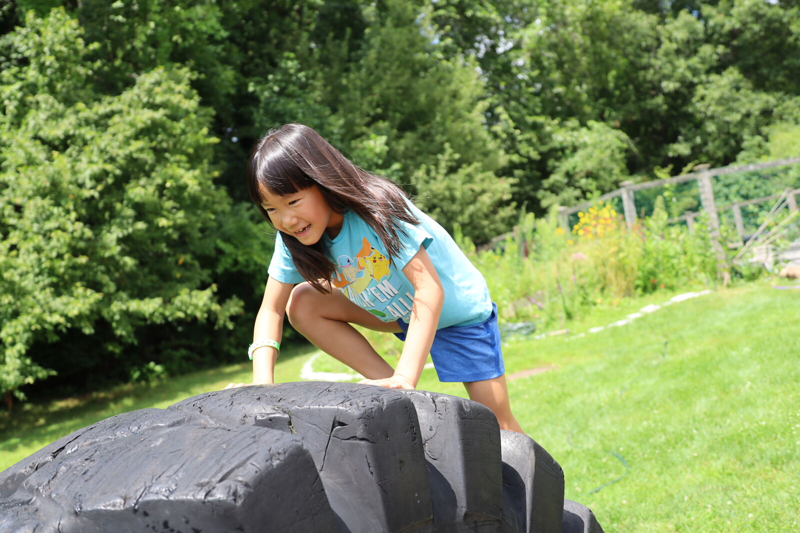 A camper building confidence on an outdoor climbing boulder